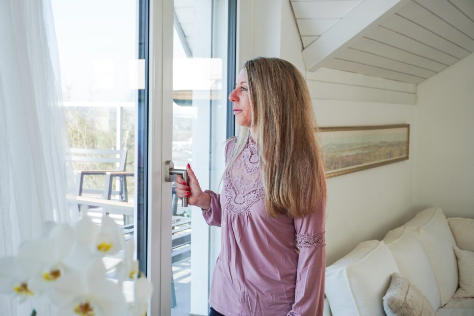 Frau öffnet modernes Fenster und blickt hinaus – Symbol für Fenstersanierung und Energieeffizienz in der Schweiz