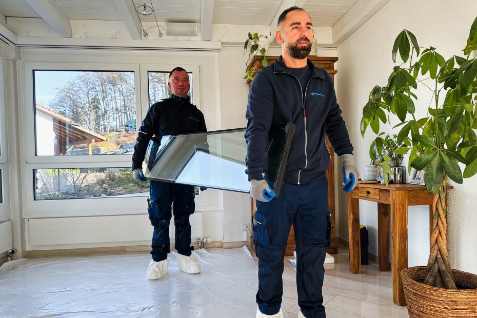 Fensterersatz bei Sanierung – zwei Monteure tragen ein neues Fenster in ein Haus in der Schweiz