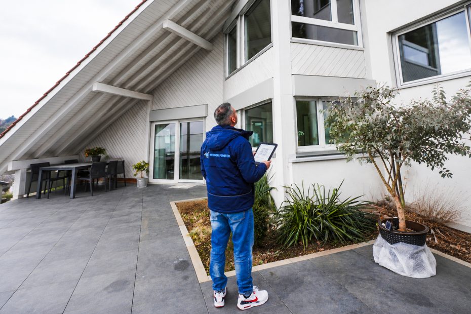 Architekt bzw. Fensterexperte von Hegner Fenster prüft mit Tablet die Planung moderner Kunststofffenster an einem Wohngebäude.