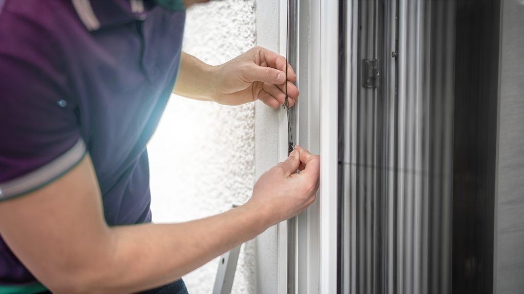 Mitarbeiter montiert einen massgefertigten Insektenschutz am Fenster von Hegner Fenster